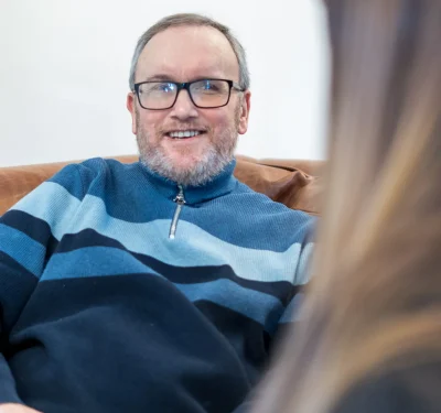 Komplex Care neurological care client smiling and having a conversation while sitting comfortably at home.