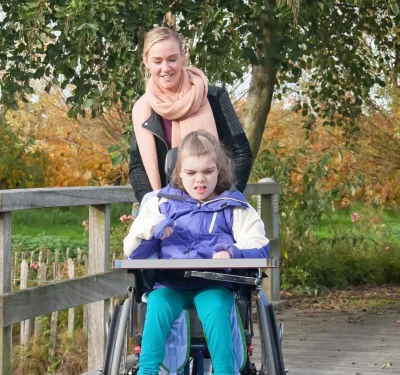 Komplex Care client in a wheelchair enjoying time outdoors with support from a family member, highlighting neuromuscular care and support.