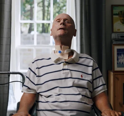 Komplex Care client sitting comfortably at home with a tracheostomy, receiving specialist complex care and respiratory support.